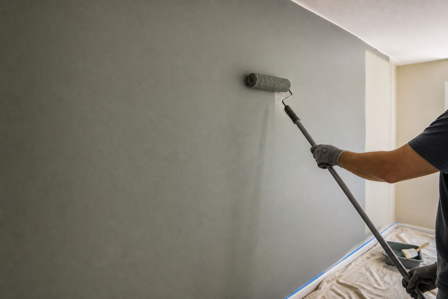 Craftsman applying final matte paint coat to a prepared wall during renovation